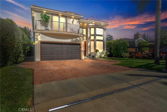 view of front of property with a tile roof, a garage, decorative driveway, a balcony, and stucco siding