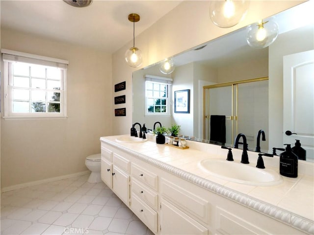 bathroom with double vanity, a sink, toilet, and a shower stall