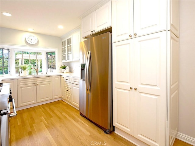 kitchen featuring a sink, stainless steel fridge with ice dispenser, light wood finished floors, and range