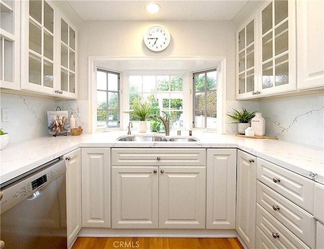 kitchen featuring stainless steel dishwasher, decorative backsplash, a healthy amount of sunlight, and a sink