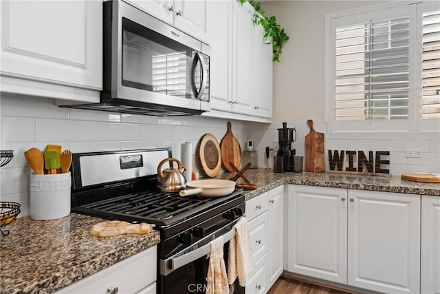 kitchen featuring white cabinetry, appliances with stainless steel finishes, dark stone countertops, and tasteful backsplash