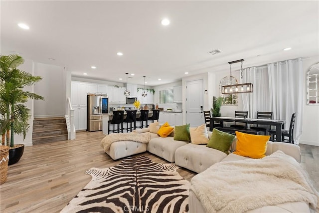living area featuring visible vents, recessed lighting, light wood-style floors, and stairway