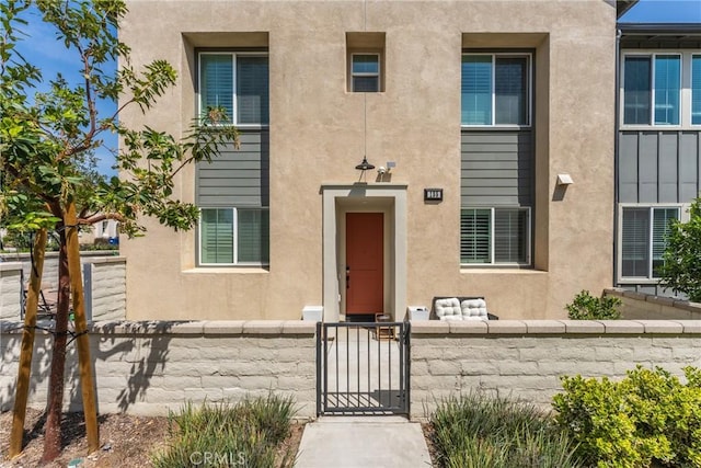 view of exterior entry featuring fence and stucco siding