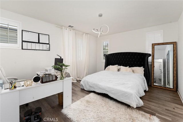 bedroom featuring baseboards, visible vents, wood finished floors, and a chandelier