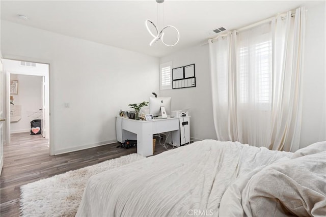 bedroom featuring visible vents, baseboards, and wood finished floors