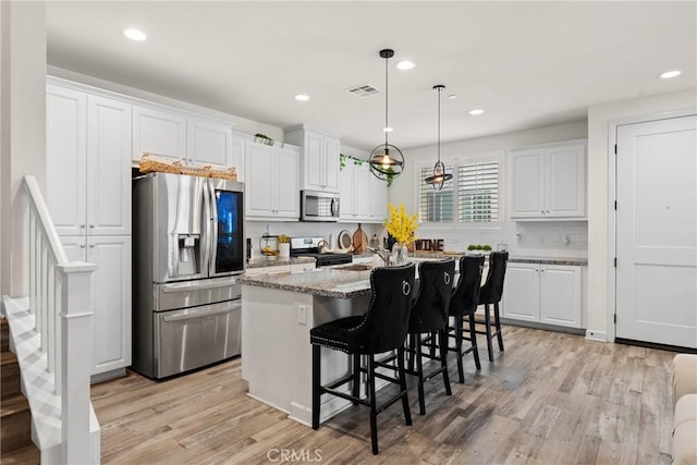 kitchen with white cabinets, stainless steel appliances, visible vents, and a kitchen island