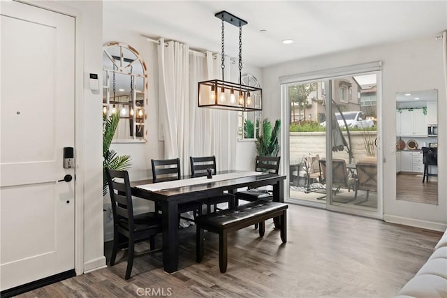 dining space with baseboards, recessed lighting, wood finished floors, and a notable chandelier