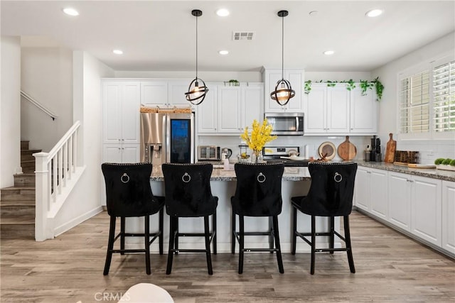 kitchen featuring a kitchen island, white cabinets, appliances with stainless steel finishes, and visible vents