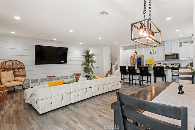 living area featuring recessed lighting, light wood-type flooring, stairs, and a chandelier