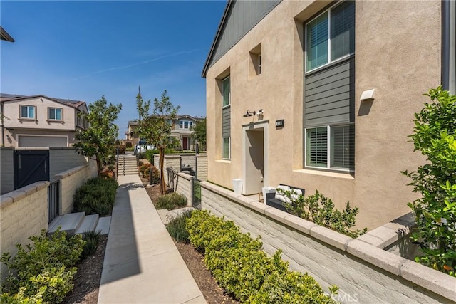 view of side of home featuring fence, stucco siding, and a residential view