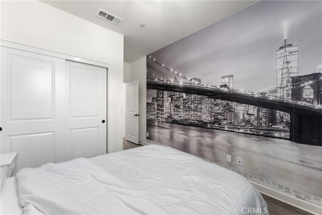 bedroom featuring a city view, visible vents, wood finished floors, and a closet