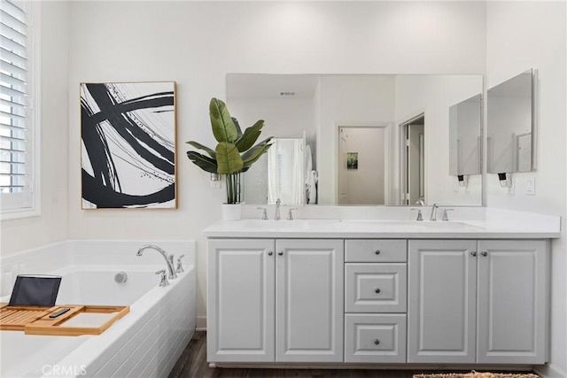 bathroom with a sink, a bath, double vanity, and visible vents