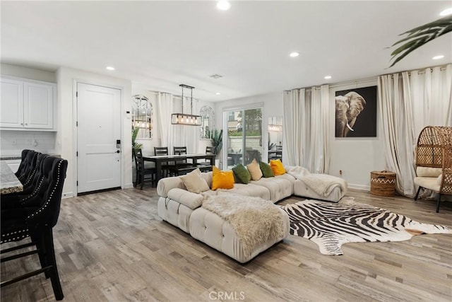living room featuring recessed lighting, an inviting chandelier, visible vents, and light wood-type flooring