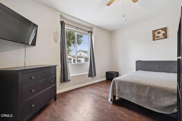 bedroom with a ceiling fan, baseboards, and dark wood-type flooring