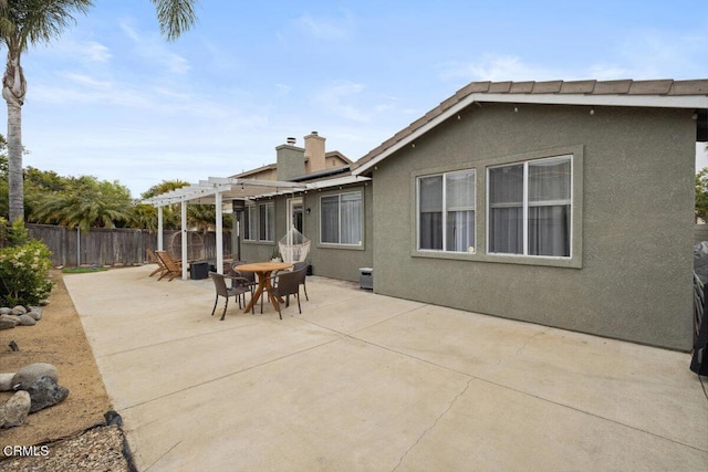rear view of property featuring fence, a pergola, stucco siding, a patio area, and outdoor dining space