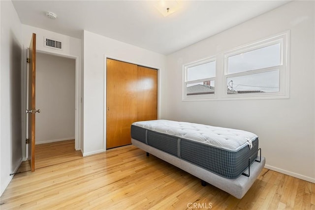 bedroom featuring baseboards, a closet, visible vents, and light wood-style floors