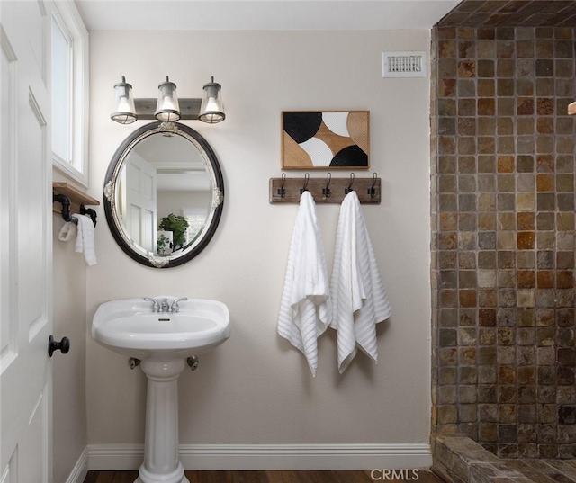 bathroom with visible vents, baseboards, and a tile shower