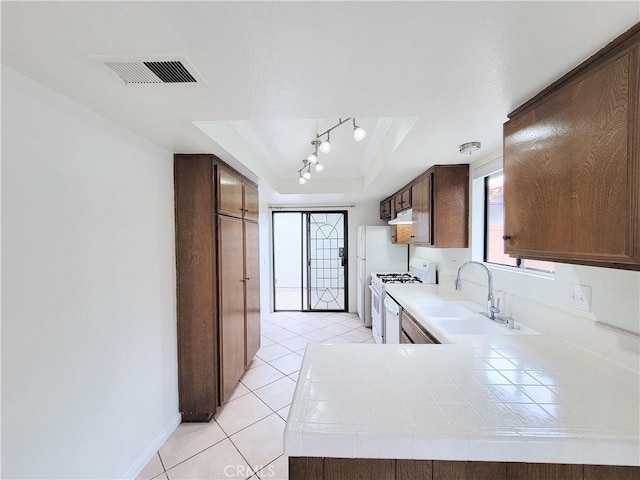 kitchen featuring white gas range oven, a sink, a raised ceiling, tile countertops, and visible vents