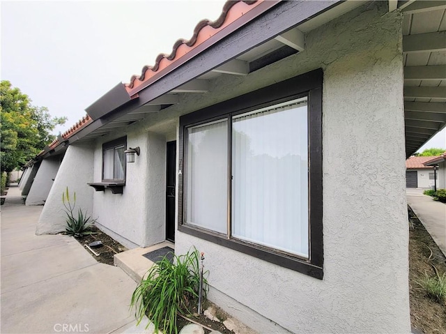 view of side of property with a tiled roof and stucco siding