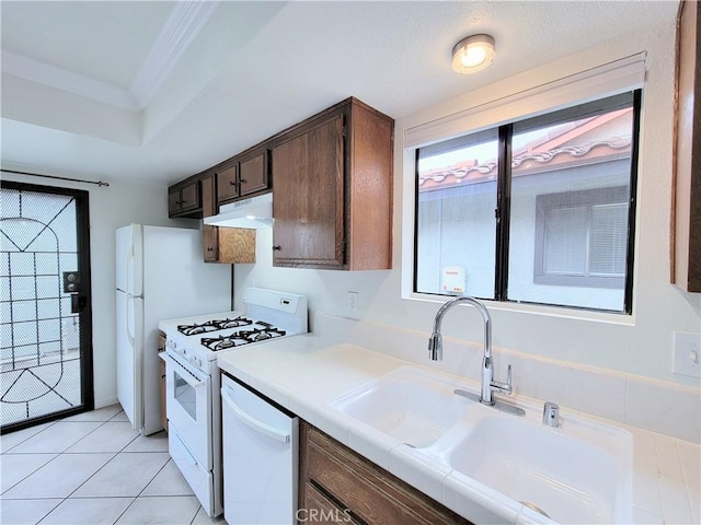 kitchen featuring crown molding, dark brown cabinetry, a sink, white appliances, and under cabinet range hood