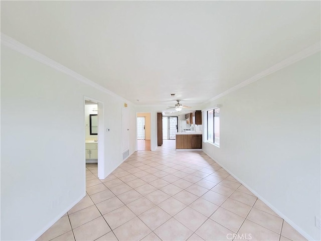 unfurnished living room featuring crown molding, visible vents, baseboards, a ceiling fan, and light tile patterned floors