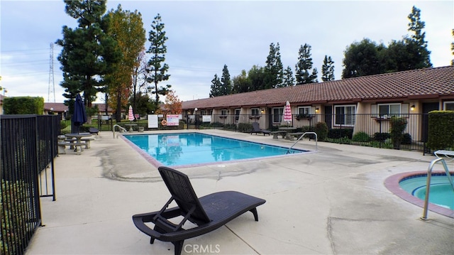 community pool with a patio and fence