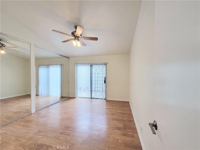 unfurnished room with a ceiling fan, baseboards, wood finished floors, and lofted ceiling