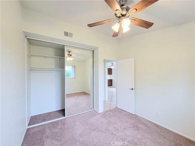 unfurnished bedroom with a ceiling fan, visible vents, baseboards, a closet, and light carpet