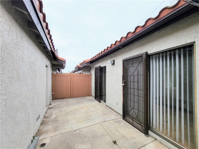 view of property exterior featuring a patio area, stucco siding, a tiled roof, and fence