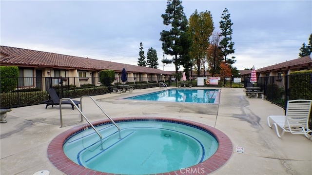 pool featuring fence, a hot tub, and a patio area