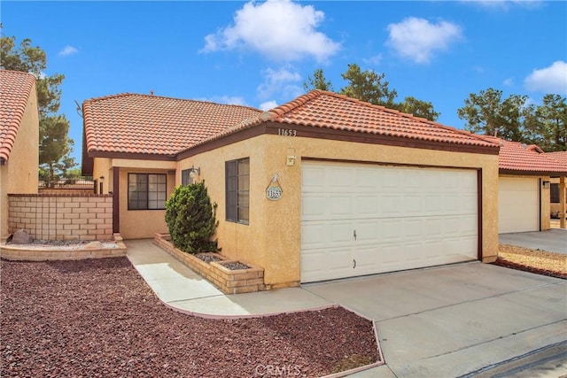mediterranean / spanish home with an attached garage, stucco siding, driveway, and a tiled roof