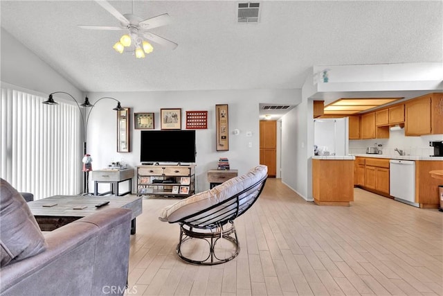 living room featuring a ceiling fan, a textured ceiling, visible vents, and vaulted ceiling