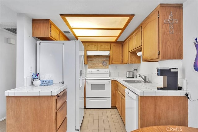 kitchen with visible vents, white appliances, tile counters, under cabinet range hood, and a sink