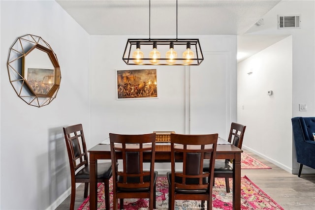 dining area featuring baseboards, wood finished floors, and visible vents