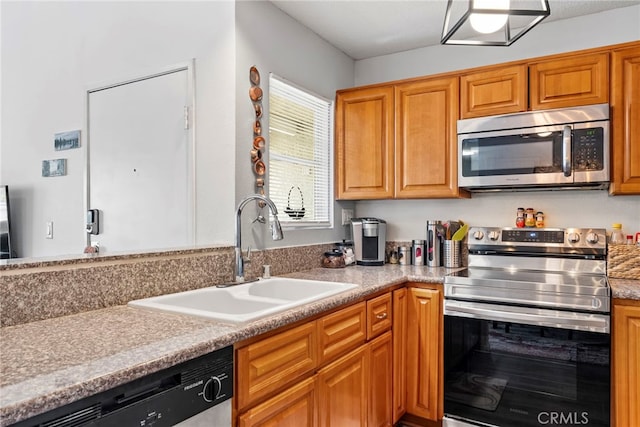 kitchen featuring brown cabinetry, a sink, light countertops, and stainless steel appliances