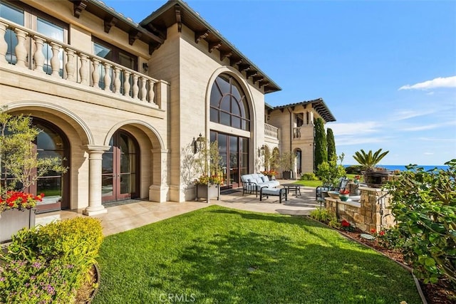 back of house with a patio, outdoor lounge area, a yard, and a balcony