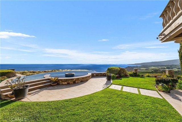 exterior space with a lawn, fence, a fire pit, and a water and mountain view