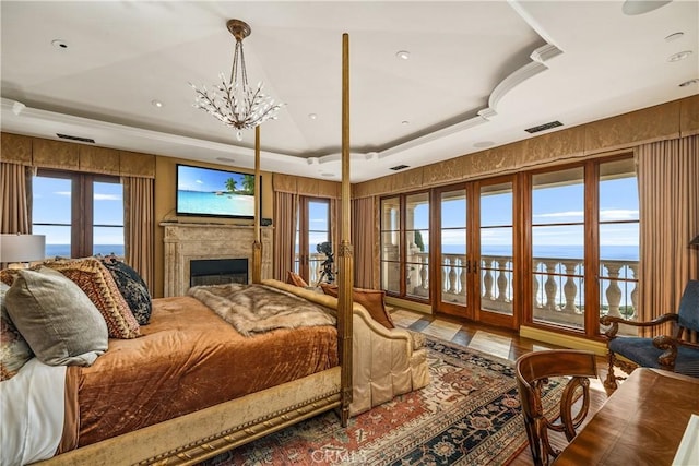 bedroom featuring a raised ceiling, a fireplace, a chandelier, access to exterior, and visible vents