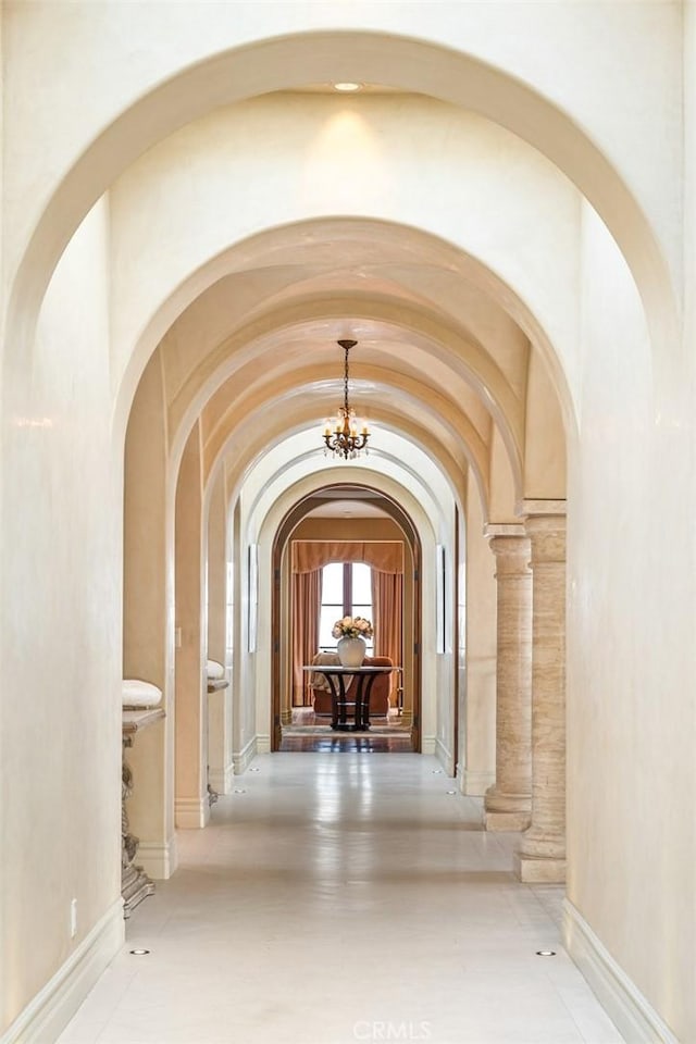 hallway featuring an inviting chandelier and arched walkways