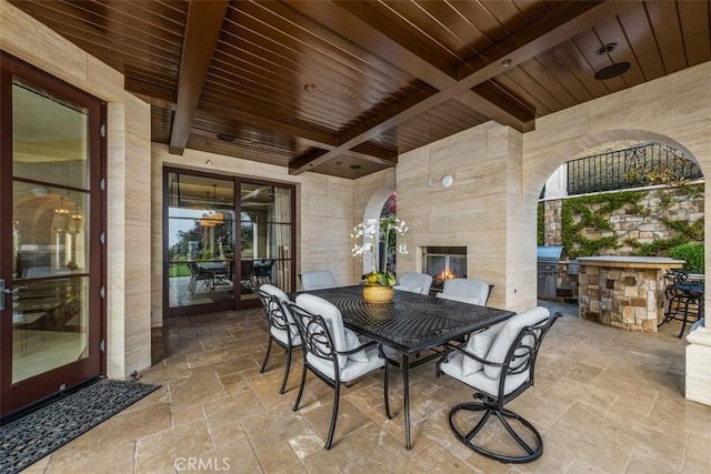 view of patio / terrace with an outdoor kitchen, a multi sided fireplace, and outdoor dining area