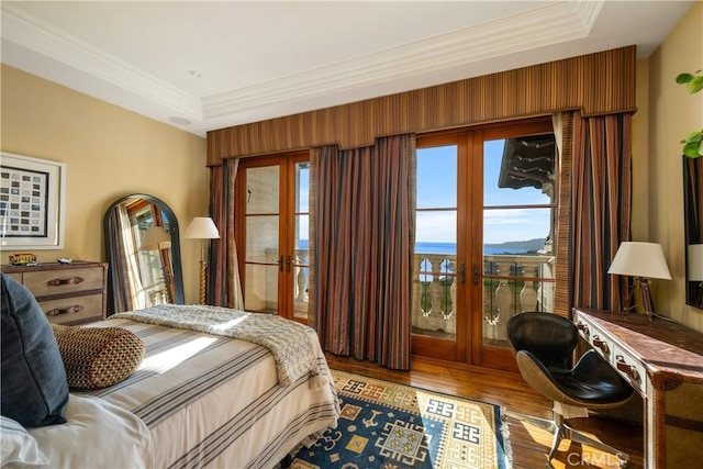bedroom with a tray ceiling, ornamental molding, french doors, and wood finished floors