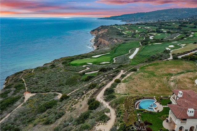 aerial view at dusk with a water view and golf course view