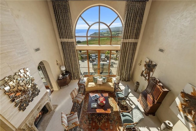 interior space with arched walkways, visible vents, a lit fireplace, and a towering ceiling