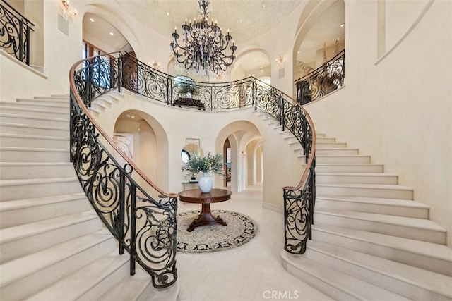 entrance foyer with stairs, a towering ceiling, recessed lighting, a chandelier, and arched walkways
