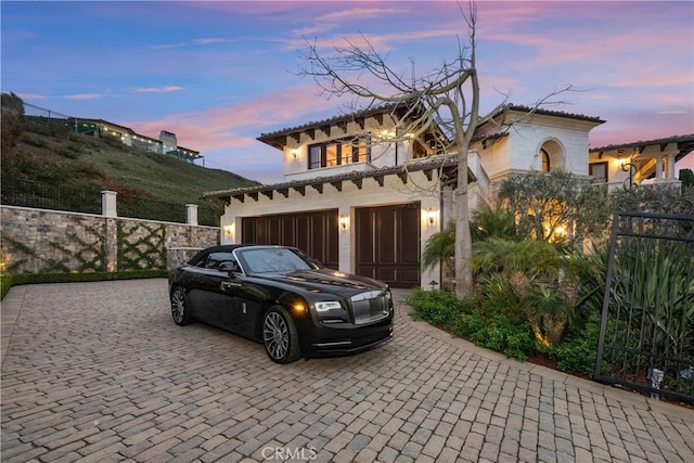 mediterranean / spanish home with decorative driveway, fence, and stucco siding