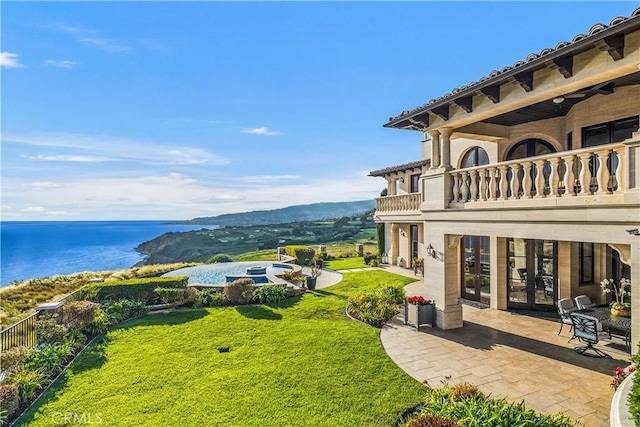 view of yard featuring a patio, a water view, a balcony, and french doors