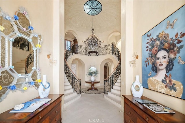 foyer featuring baseboards, arched walkways, a chandelier, and stairway