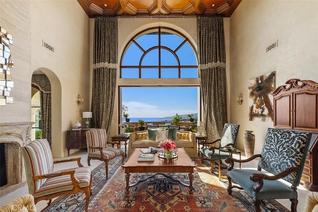 living area with arched walkways, visible vents, ornamental molding, and a towering ceiling