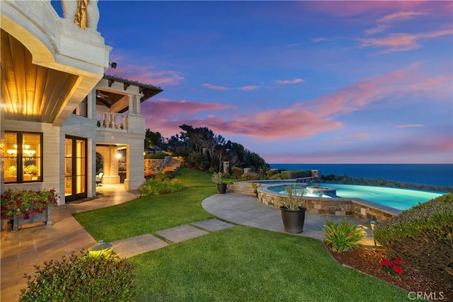 view of pool featuring a yard, a patio, an in ground hot tub, and a water view