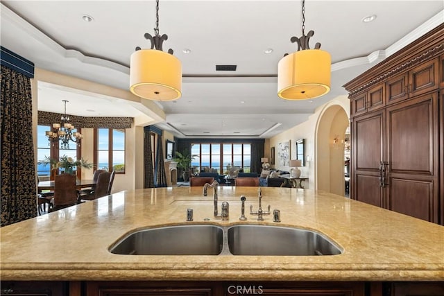 kitchen with visible vents, decorative light fixtures, light stone countertops, a sink, and open floor plan